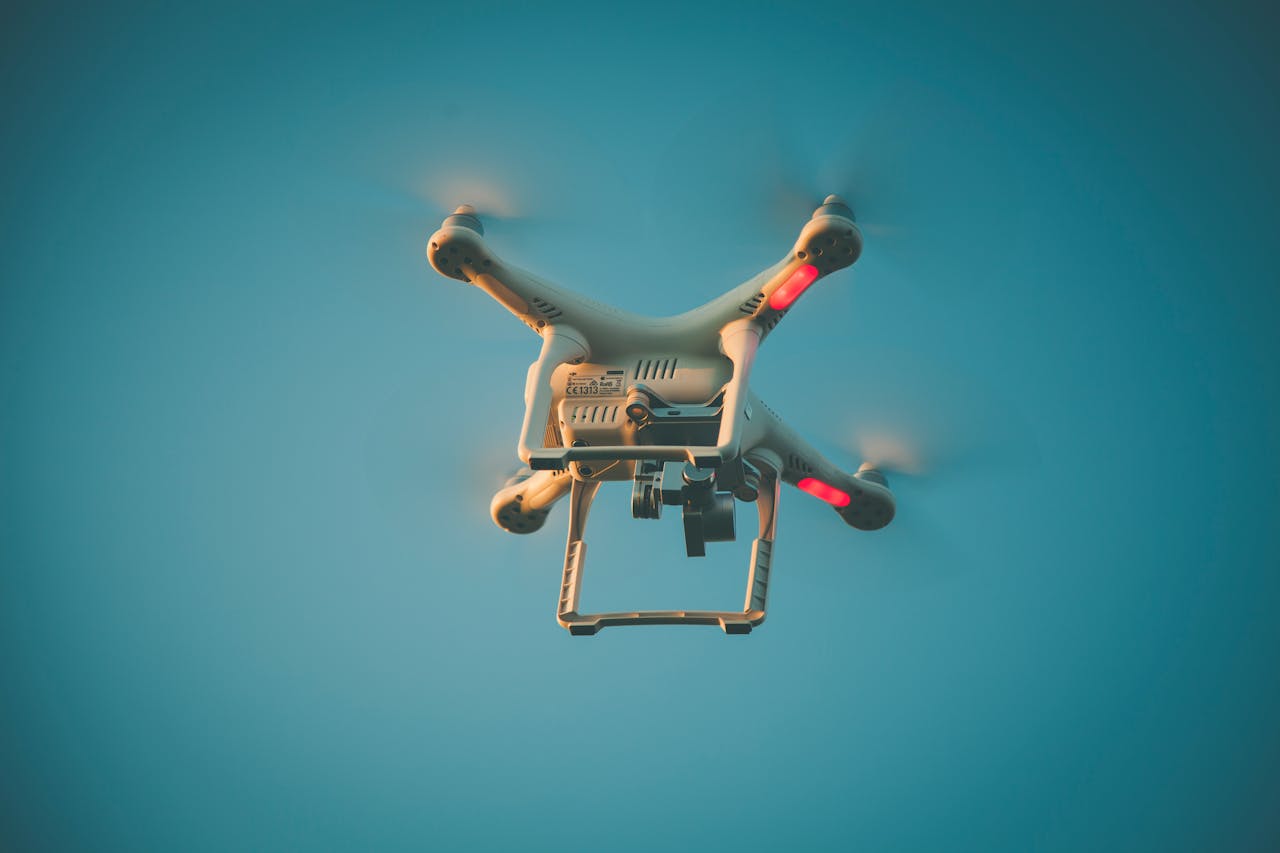 A drone in flight against a clear blue sky, showcasing modern technology.